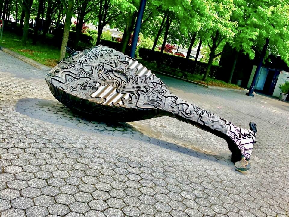 Giant sculpted ukulele lying across a paved plaza in New York